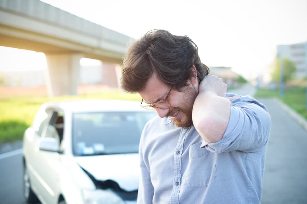 After a painful car collision in Miami, FL, a man holds his injured neck